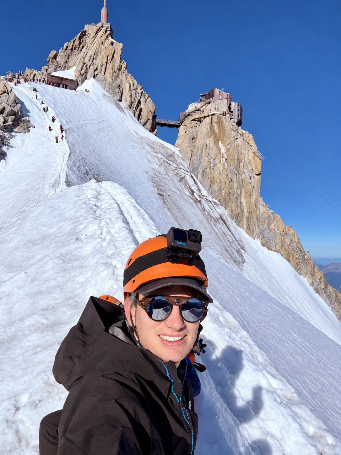 Alpiniste casqué se photographiant sur une arête enneigée